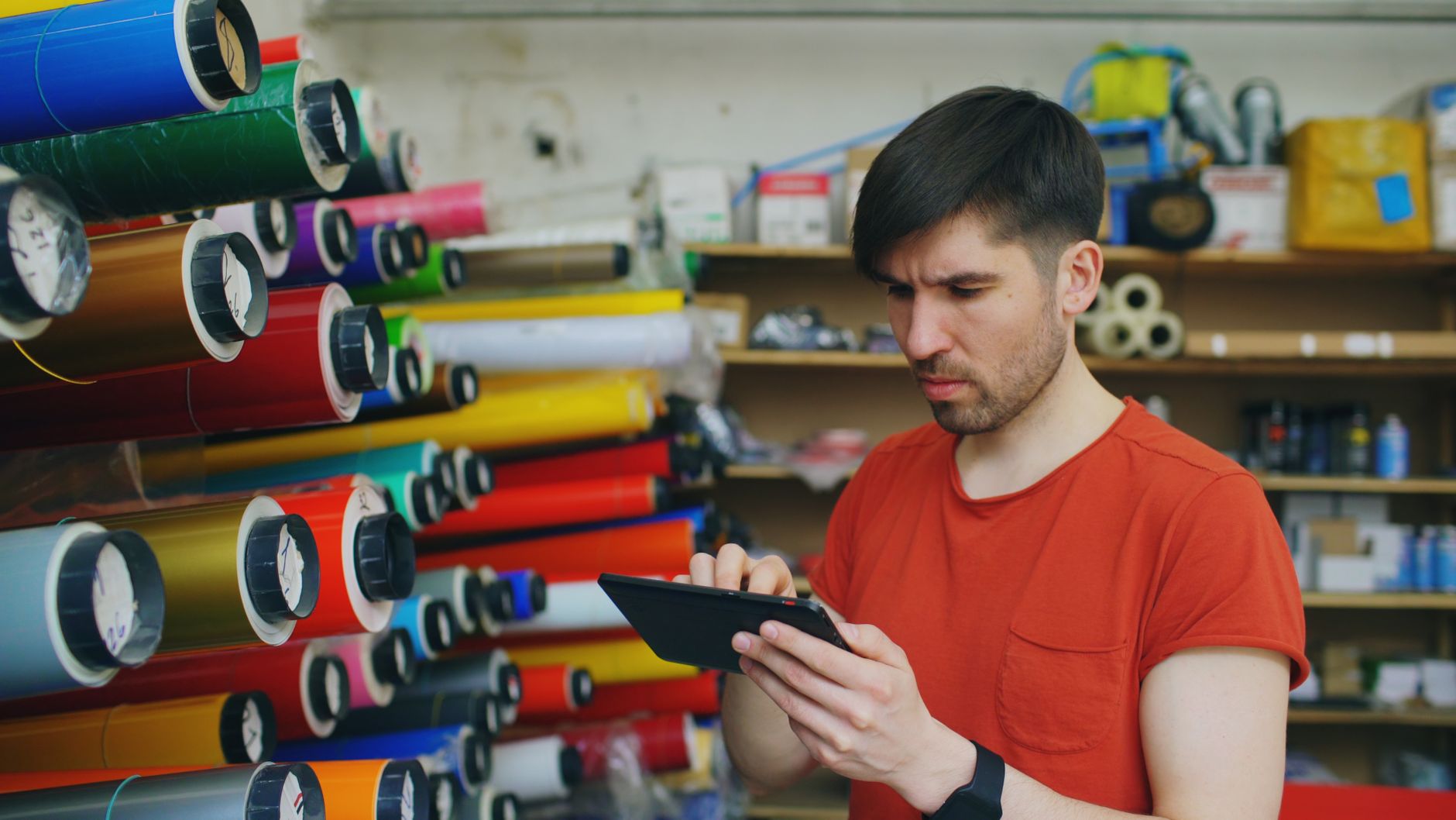 Un artisan sous-traitant consulte sa tablette pour gérer sa facturation dans son atelier