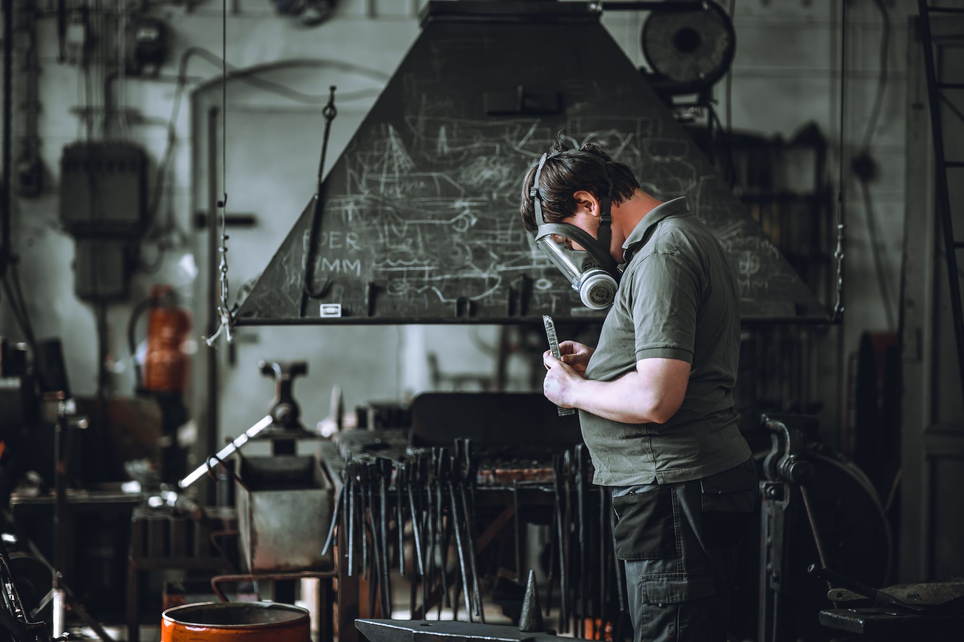Artisan dans son atelier industriel, consultant son smartphone entre deux tâches