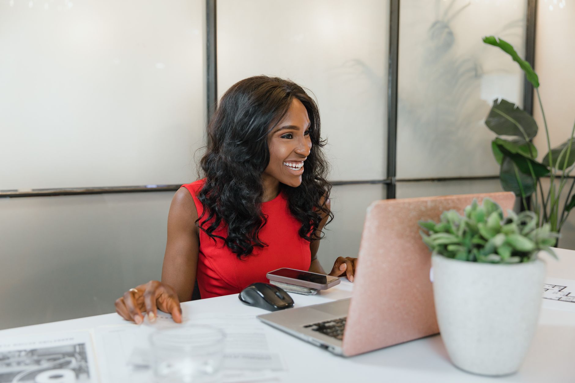 Une consultante souriante gère ses abonnements clients depuis son ordinateur portable, dans un bureau lumineux