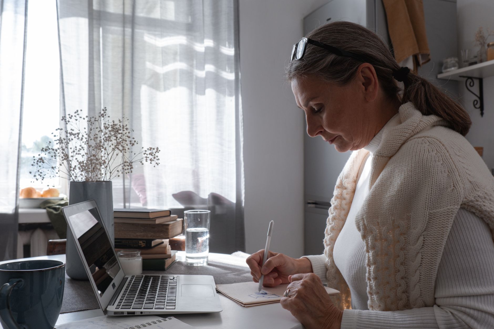 Une indépendante prépare son budget prévisionnel à son bureau, carnet ouvert et ordinateur portable