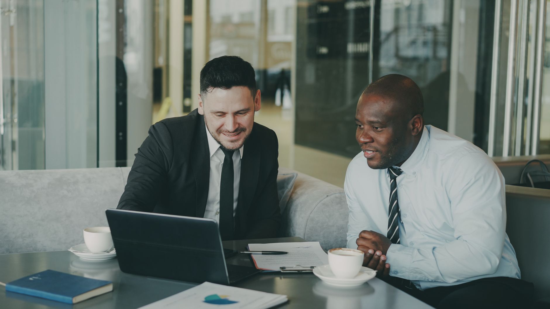 Une entrepreneure et un investisseur échangent avec confiance autour d'un ordinateur portable et de documents, ambiance conviviale
