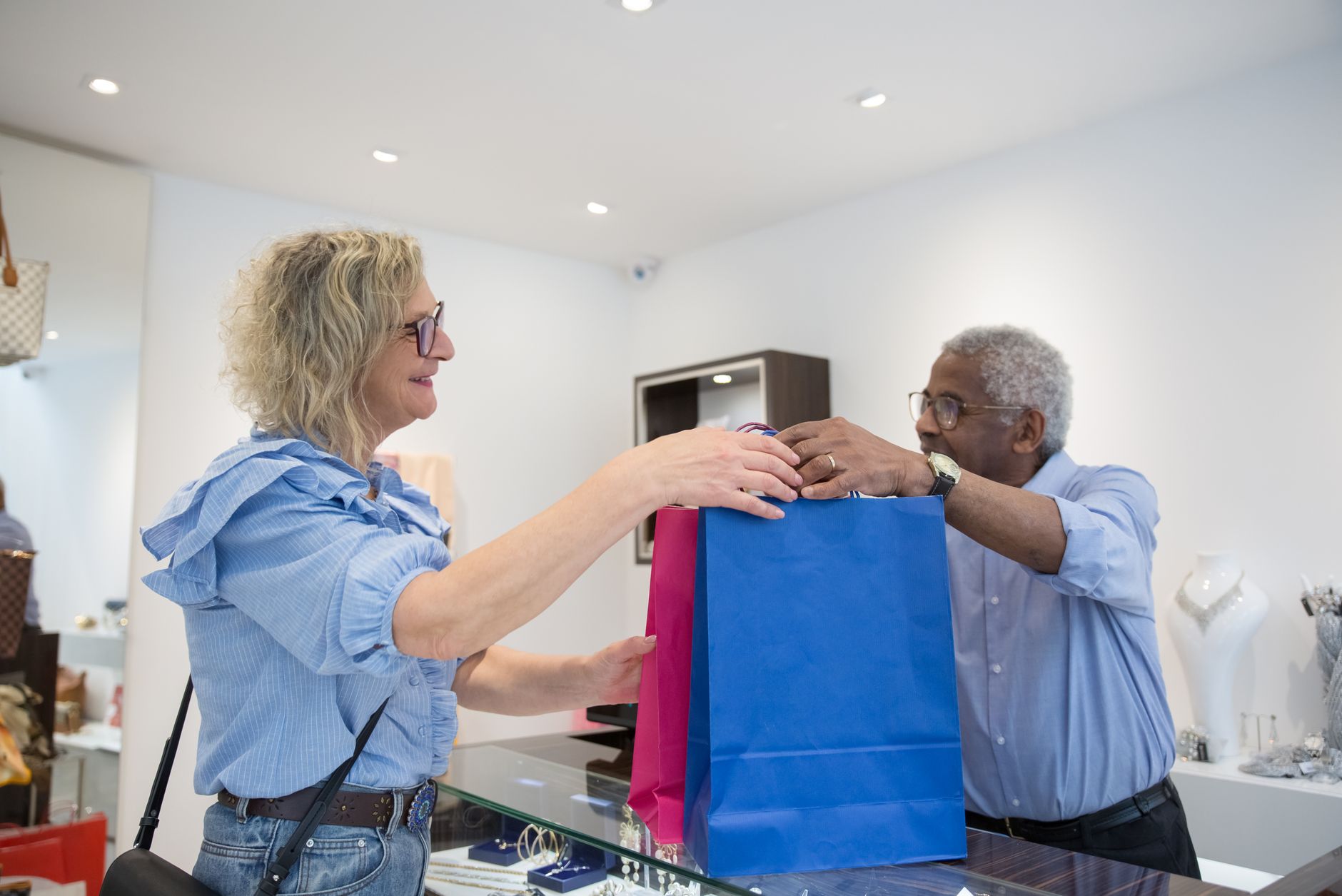 Un commerçant remet des sacs de commande à une cliente souriante au comptoir de sa boutique