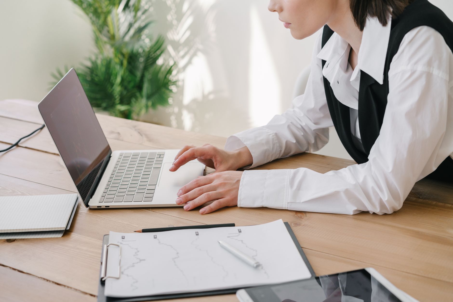 Une dirigeante consulte sereinement une facture sur son ordinateur portable, à un bureau soigné et lumineux